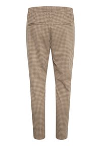 Beige rutiga byxor med elastisk midja, två bakfickor och avsmalnande ben. Slät tygtextur.