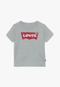 T-shirt gris à manches courtes pour tout-petit avec logo Levi's rouge et blanc sur la poitrine et petite étiquette rouge Levi's sur la couture latérale.