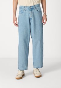 Jeans de denim de color azul claro con un ajuste relajado, piernas rectas, una cintura de altura media y bolsillos frontales. Terminados con un cierre de botón y cremallera.