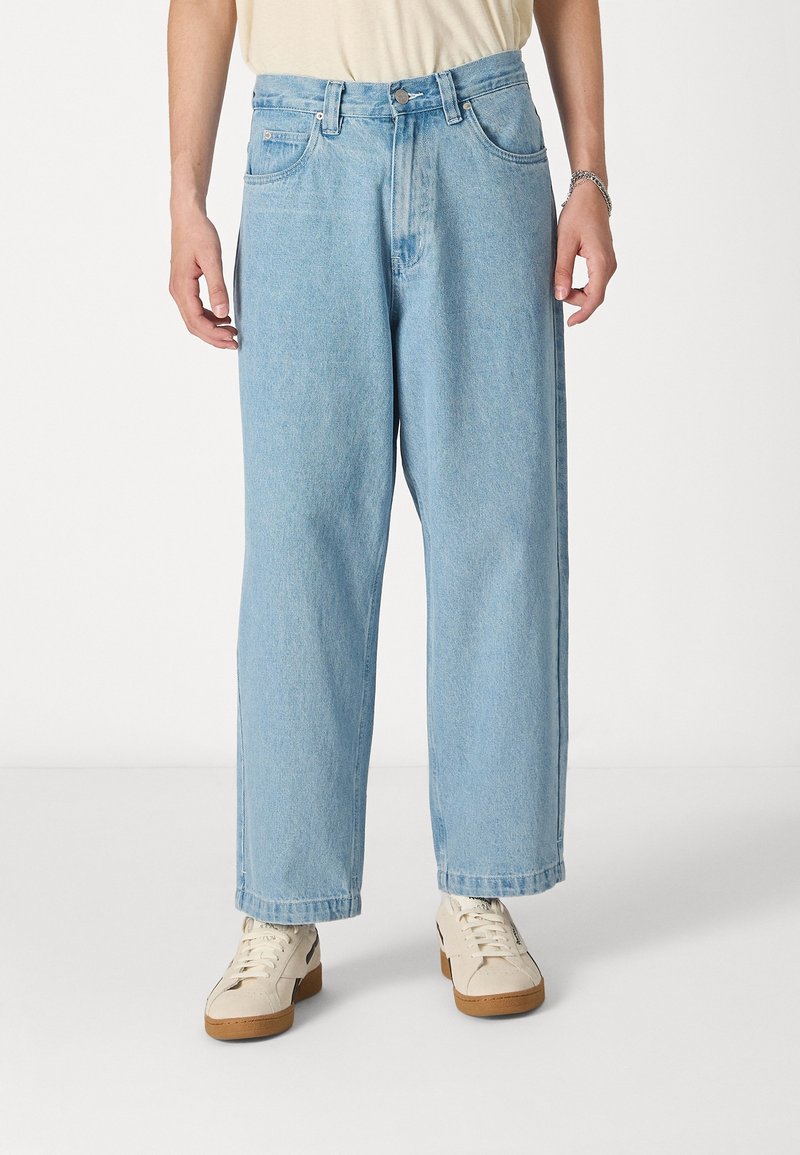 Jeans de denim de color azul claro con un ajuste relajado, piernas rectas, una cintura de altura media y bolsillos frontales. Terminados con un cierre de botón y cremallera.