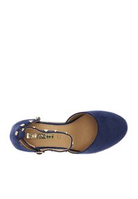 Sininen mokkanahkainen slingback-kengät, joissa on pyöreä kärki, ruskea sisäpohja ja koristeelliset kultaiset niitit yläremmissä. Merkkilogo näkyvissä.