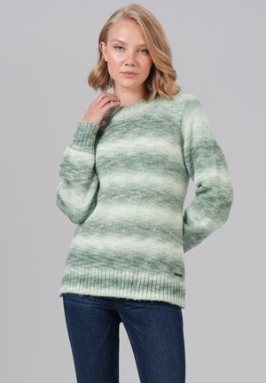 Groene en crèmekleurige gestreepte trui met een zachte textuur, brede halslijn en ribgebreide zoom. Gedragen met donkere jeans, poseert het model met een hand op de nek.