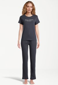 Svart bomullspyjamas set bestående av en T-shirt med kort ärm och logotyp samt långa byxor med en bekväm passform. Mjuk textur och minimalistisk design.