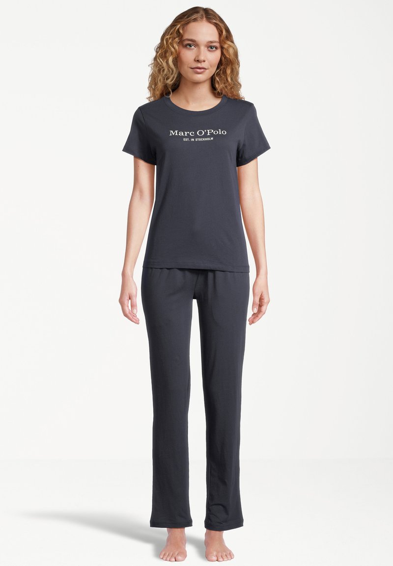 Svart bomullspyjamas set bestående av en T-shirt med kort ärm och logotyp samt långa byxor med en bekväm passform. Mjuk textur och minimalistisk design.