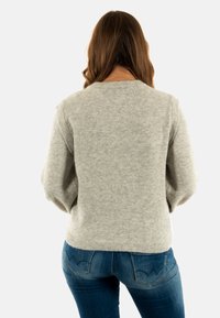 Pullover grigio chiaro a maglia con scollatura rotonda e vestibilità ampia. Maniche a costine e orlo, con tessuto texture. Abbinato a jeans blu scuro.