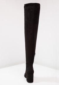 Černé semišové boty nad kolena s masivním podpatkem, hladkým povrchem, přiléhavým designem a bočním zipem.