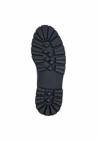 Semelle en caoutchouc noir avec des motifs de crampons prononcés, comprenant des designs hexagonaux et en zigzag pour une adhérence optimale. Surface texturée pour une meilleure prise.