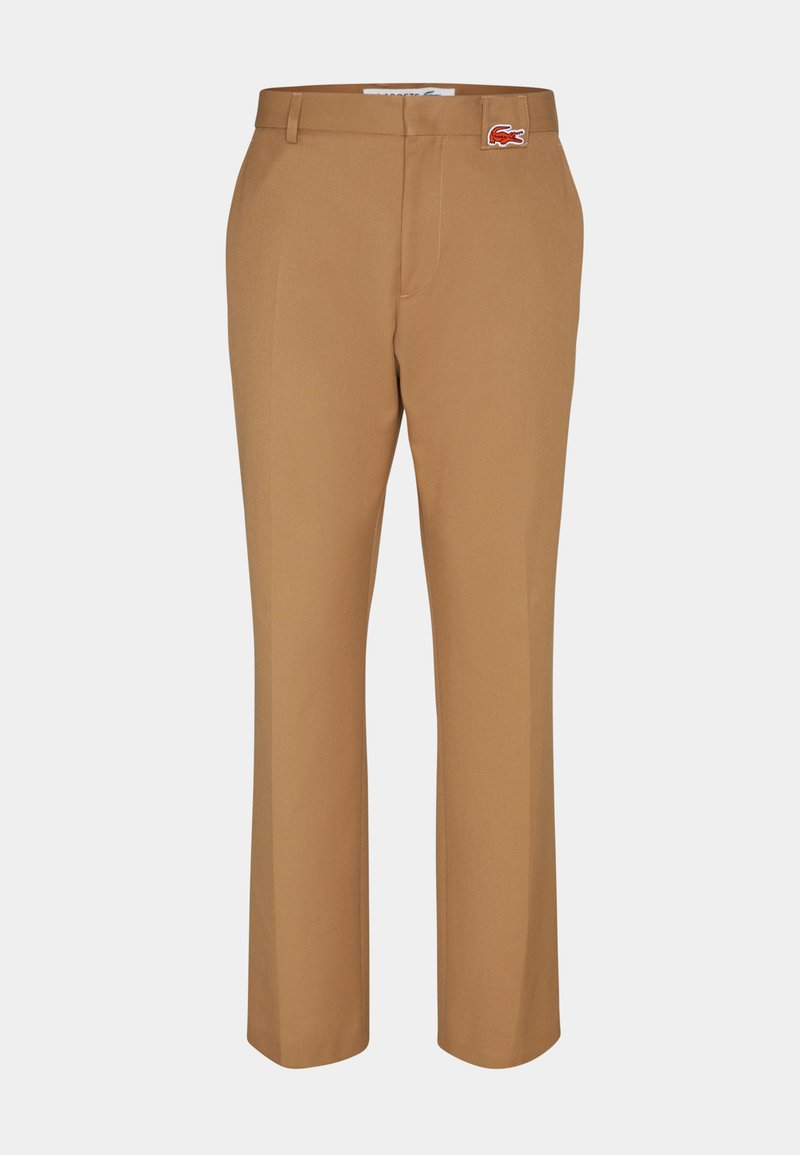 Pantalons marron en tissu lisse. Design à jambe droite avec une poche avant et un petit patch logo Lacoste rouge près de la taille.