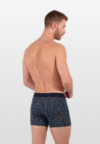 Marineblauwe boxershort met abstracte ontwerpen in oranje en teal; elastische tailleband; aansluitend ontwerp; geen zichtbare hardware.