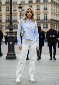 Svetlomodrá košeľa s golierom a dekoratívnymi gombíkmi, v páre s bielymi širokými nohavicami a robustnými bielymi čižmami. Malá strieborná kabelka.