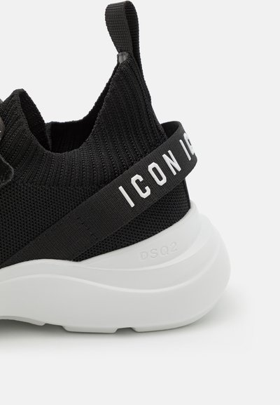 Sneaker nera in maglia con upper testurizzato, caratterizzato da un marchio bianco su una fascia e una suola in gomma bianca chunky.