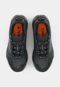 Paire de chaussures de randonnée Adidas Terrex noires et grises avec semelles intérieures orange et lacets à motifs, vues de dessus sur fond blanc.