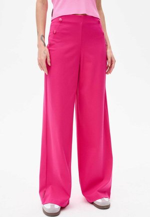 Jasnoróżowe spodnie typu wide-leg z gładkiego materiału, z dwoma dekoracyjnymi guzikami z przodu i luźnym krojem.
