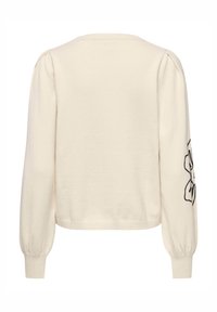 Kremfarvet sweater med lange, puffede ærmer. Har sort blomsterbroderi på det ene ærme og en ribbet kant. Blød, strikket tekstur.