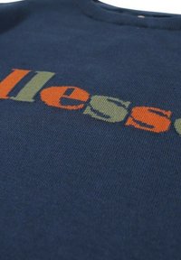 Sweat-shirt en maille marine avec un texte coloré en orange et vert. Encolure ronde avec une texture douce et un tissu de poids moyen.