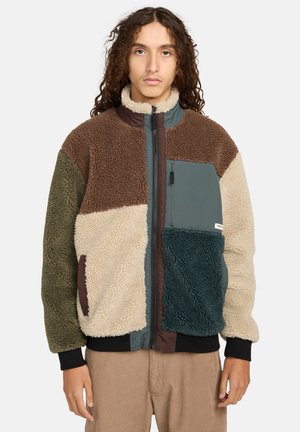 Fleece jacket featuring a patchwork design in tan, brown, green, and teal. High collar with zipper, front pocket, and textured fabric.