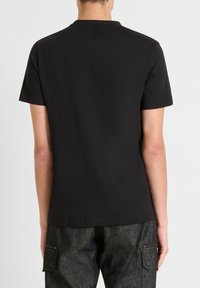 Zwarte katoenen t-shirt met korte mouwen, ronde hals en een eenvoudig ontwerp. Glad textuur, geen zichtbare patronen of accenten.