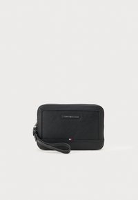 Mustast nahkklamber, tekstureeritud pinnaga, ristkülikukujuline ja randme rihmaga. Omab logosilti ja väikest triivärvi aktsenti.