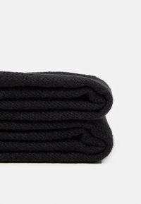 Couverture en polaire noire, soigneusement pliée, mettant en valeur une texture douce et une épaisseur uniforme. Les bords sont nets sans motifs visibles ni matériel.