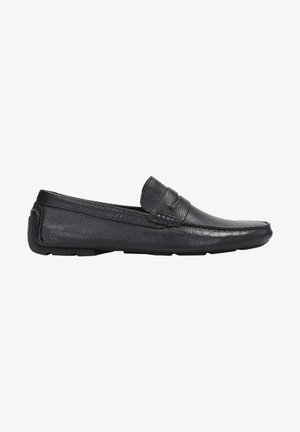 Mocassins en cuir noir avec une texture lisse, un profil bas, un design à enfiler et des coutures minimales sur le devant et les côtés.