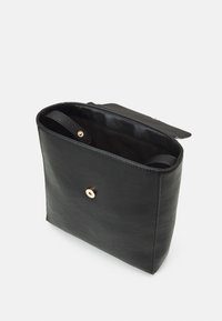 Bolso de cuero negro con forma rectangular, que presenta una textura suave, cierre de broche dorado y una correa interior.