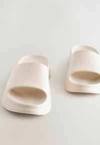 Hvide slidesandaler med en bred rem og åben tå-design. Glat tekstur med afrundede kanter og en formet sål for komfort.