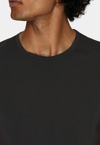 T-shirt a girocollo grigio scuro realizzato in morbido tessuto di cotone, con maniche corte e un design minimalista senza motivi o accenti visibili.