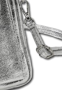 Zilveren metalen schoudertas met een gestructureerde afwerking, voorzien van een afneembare riem en een zilveren metalen sluiting voor een veilige sluiting.