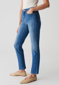 Jeans in denim blu con vita alta, vestibilità slim e design a cinque tasche, arricchiti da una texture liscia e una leggera sfumatura.