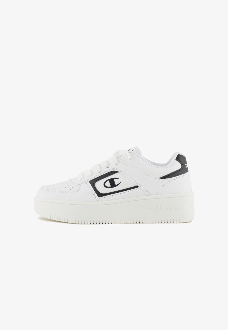 White sneakers with a smooth leather upper, black accents, rounded toe, flat laces, and a textured, thick sole featuring a logo detail.