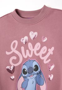 Sudadera de algodón en malva apagado con cuello acanalado. Presenta un personaje impreso y corazones con lentejuelas en tonos rosas, con el texto que dice "Dulce."