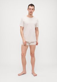 Beige Baumwoll-T-Shirt und passende Shorts, glatte Textur, klassischer Rundhalsausschnitt, kurze Ärmel, figurbetonte Passform, minimalistisches Design, keine Muster oder Akzente.
