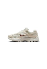 Zapatilla de running Nike beige claro con paneles de malla, suela acolchada y un logo Swoosh de color bronce en el lateral.