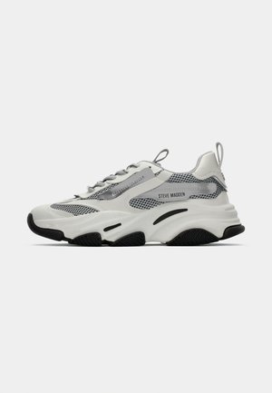 Baskets de sport blanches avec des panneaux en maille, des accents gris et des semelles en caoutchouc noir. Comprend des lacets, une languette de traction et un marquage de la marque.
