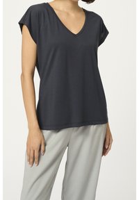 Mørkeblå kortærmet top med V-udskæring, lavet af blødt stof; har en afslappet pasform og glat tekstur, parret med lysegrå bukser.