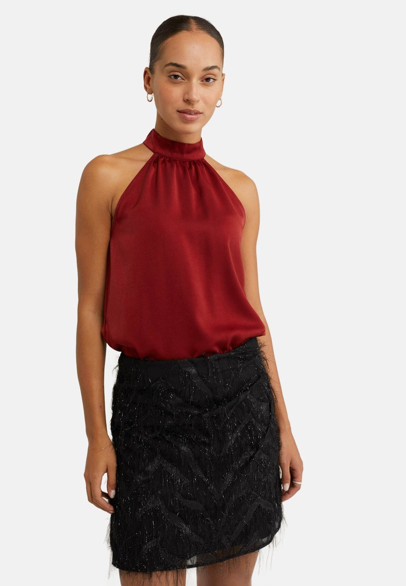 Červený saténový halter top kombinovaný s černou texturovanou sukní z peří s cik-cak vzorem a lehce průhledným překryvem.