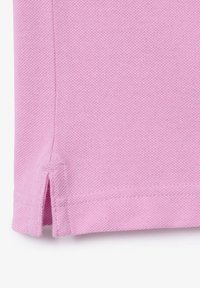 Rosa bomulls tyg med en strukturerad yta, med sidoklaffar vid fållen och fina sömnadsdetaljer. Formen är avslappnad och informell.