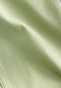 Hellgrüner strukturiertes Gewebe mit einem subtilen Webmuster, das eine glatte Oberfläche und einen weichen Fall aufweist. Die Farbe wirkt frisch und gedämpft.