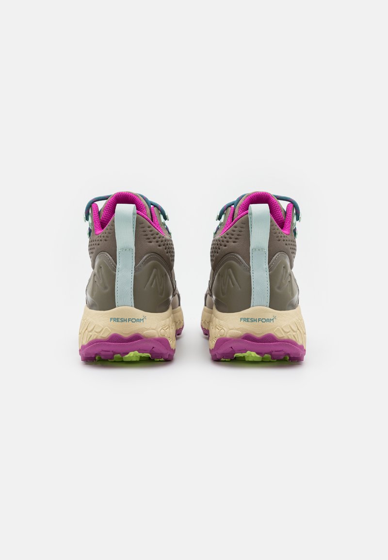 Zapatillas deportivas con una parte superior gris, acentos en lavanda y una entresuela cremosa acolchada. Presenta una suela exterior texturizada de color púrpura oscuro y un diseño ventilado.