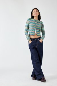 Gestreifte, kurz geschnittene Strickjacke in Pastellfarben, kombiniert mit hoch taillierten dunkelblauen Denim-Hosen. Knopfverschluss und zwei sichtbare Seitentaschen.