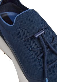 Marinblå stickad sneakers med texturerad ovandel, runda snören och en flexibel sula med en ljus accent på nederkanten.