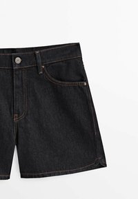 Svarta denimshorts med standard passform. Funktioner inkluderar en midjebandknapp, orange söm och framfickor. Slät struktur.