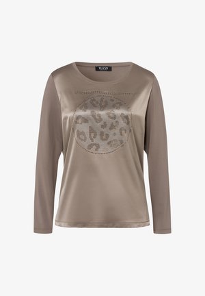 Chemise beige à manches longues, ornée d'un motif léopard rond souligné de clous métalliques. Tissu lisse avec une coupe décontractée et un col rond.
