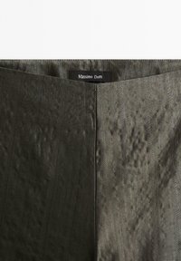 Mörk olivgrön tyg med en silkeslen textur, med vertikala ränder och en sydd etikett som säger "Massimo Dutti" vid midjan.