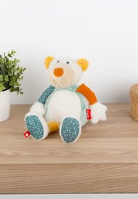 Soft toy bear with a white, textured body, orange nose, and ears. Features colorful fabric patches in green, teal, and orange.