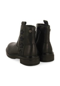 Stivaletti neri in pelle con finitura liscia, pannelli laterali elastici e un motivo a stella decorativo cucito sul tallone esterno.