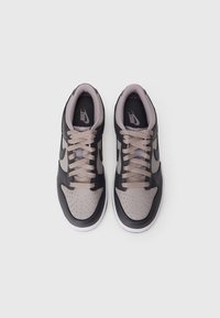 Czarno-szare sneakersy Nike z perforowanym noskiem, jasnoszarymi sznurówkami, wyściółką na kołnierzu oraz białą podeszwą środkową.