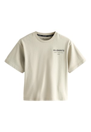 Bambino con capelli ricci che si gira di lato, indossa una maglietta beige ALLSAINTS con testo nero e caratteri giapponesi sulla schiena.