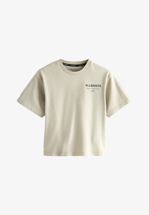 Barn med krøllet hår, der vender sig til siden, iført en beige ALLSAINTS T-shirt med sort tekst og japanske tegn på bagsiden.