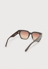 Óculos de sol de plástico castanho com formato olho de gato, lentes graduadas que passam do rosa claro ao escuro, e hastes finas e arredondadas.